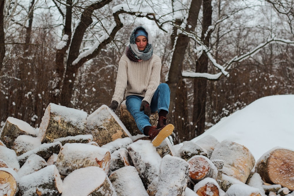 woman in white winter coat sitting on brown log during daytime