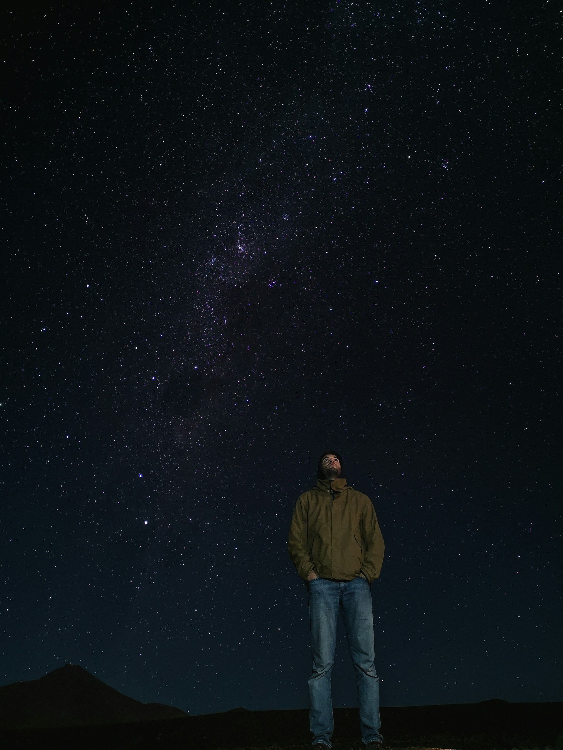 man in brown jacket standing under starry night