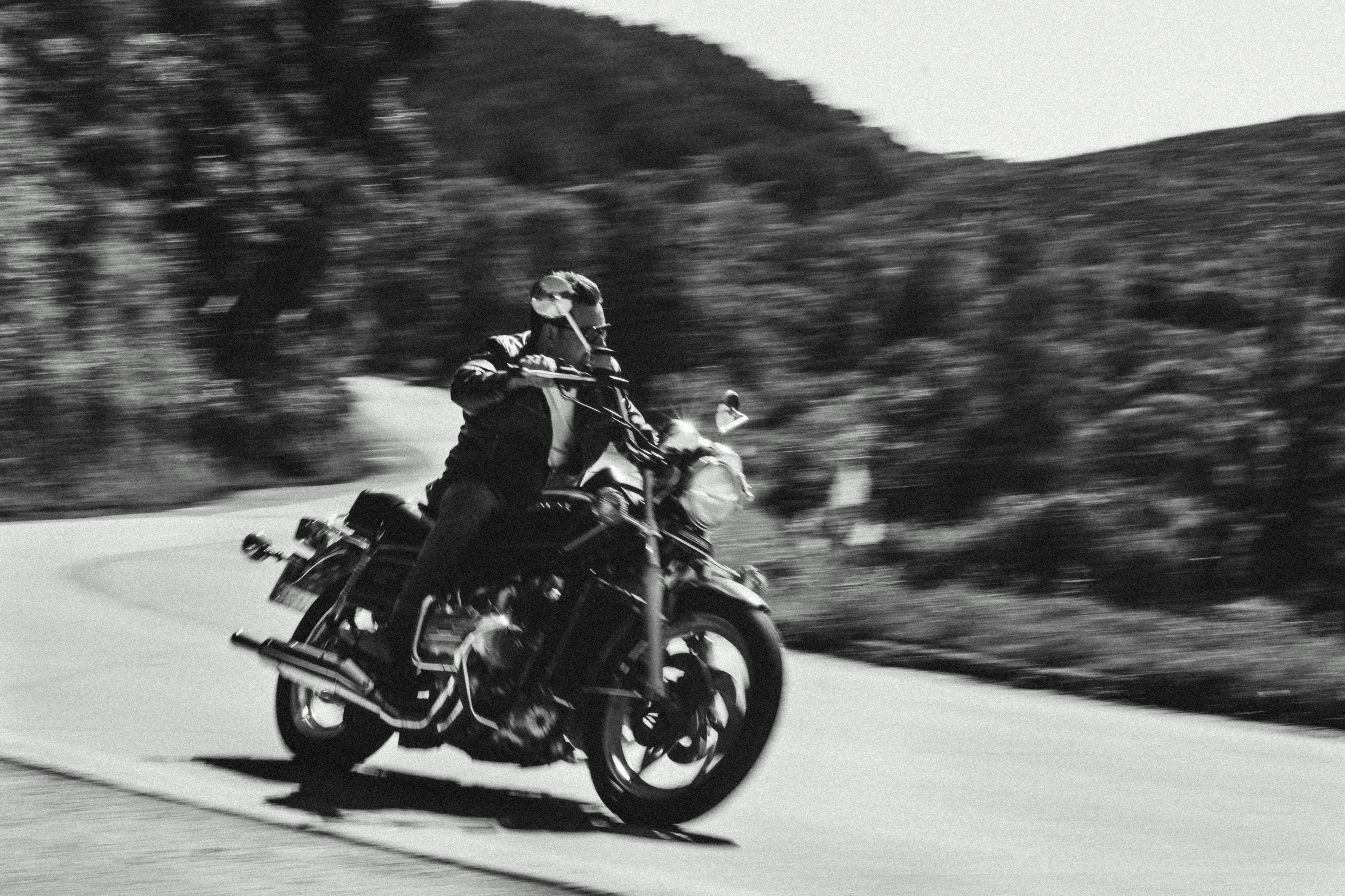 grayscale photo of man riding motorcycle