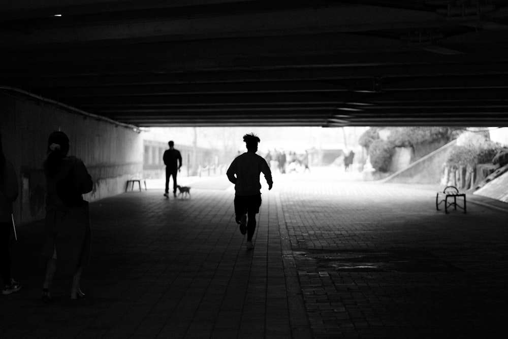 grayscale photo of man and woman walking on hallway