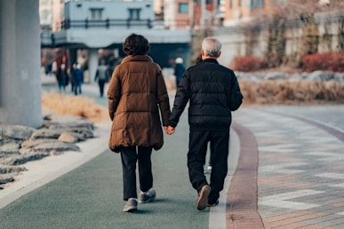 man in brown jacket and gray pants walking on sidewalk during daytime