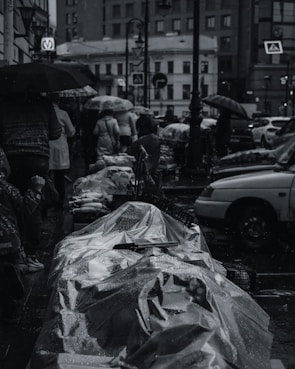 A rainy day scene with people holding umbrellas in a Thai city.