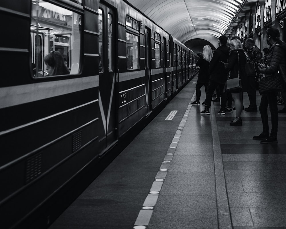 grayscale photo of people walking on train station