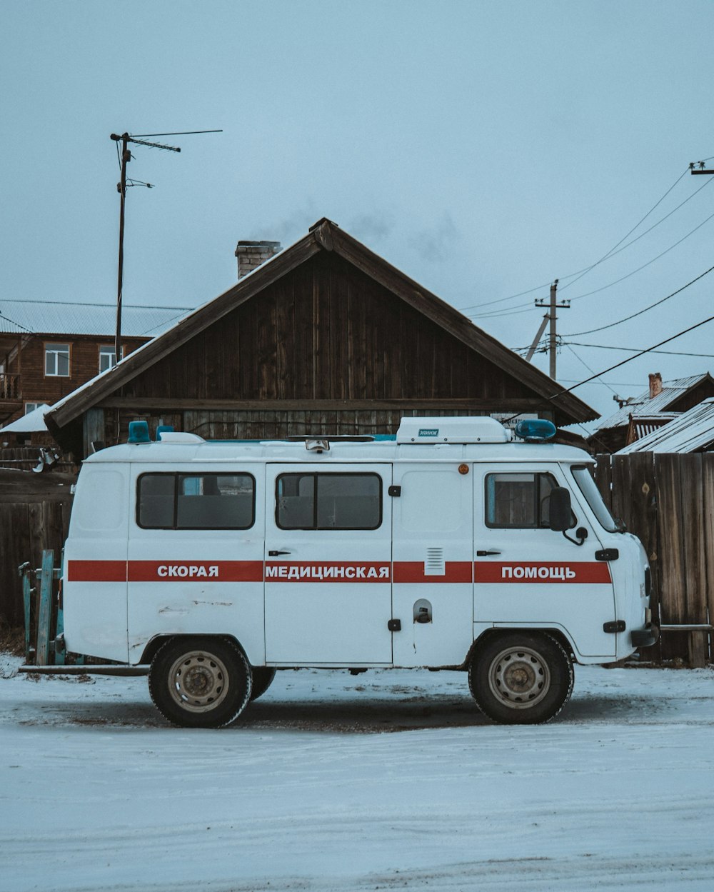 red and white fire truck parked beside brown wooden house during daytime