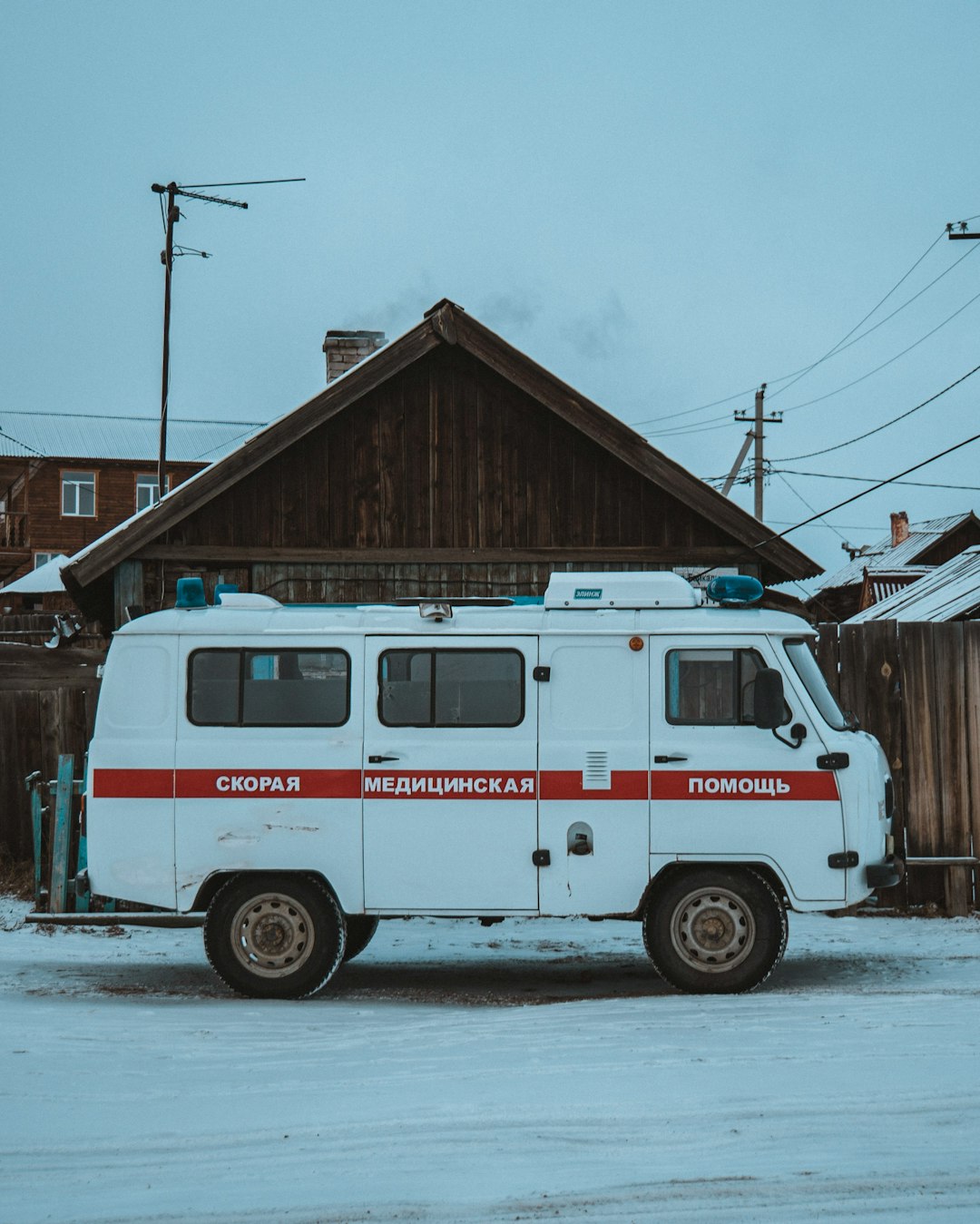 red and white fire truck parked beside brown wooden house during daytime