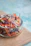 A close-up of a translucent plastic deli container filled with colorful fresh salad.