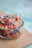 A close-up of a translucent plastic deli container filled with colorful fresh salad.