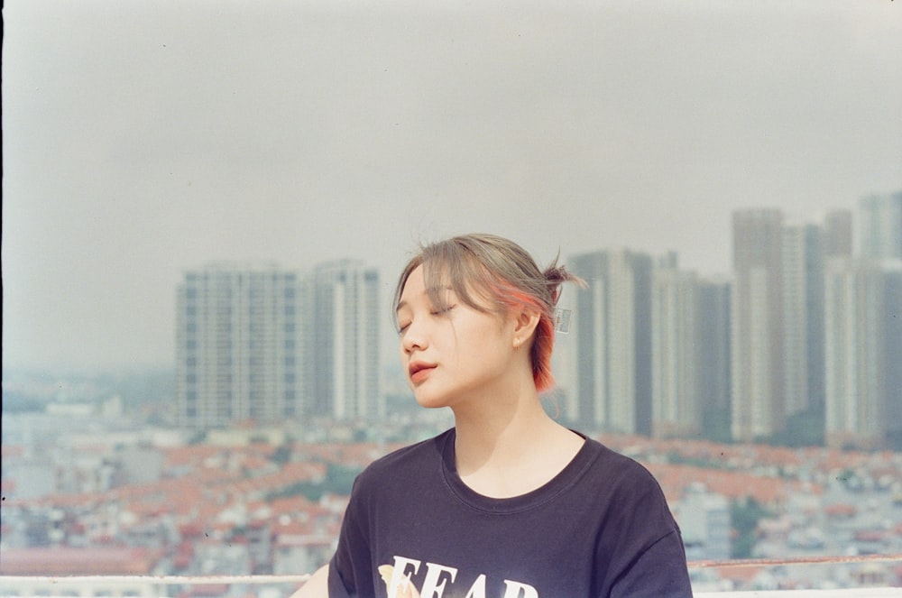 woman in black and white crew neck t-shirt standing on top of building during daytime