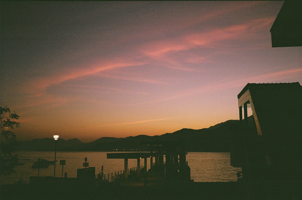 silhouette of building near body of water during sunset