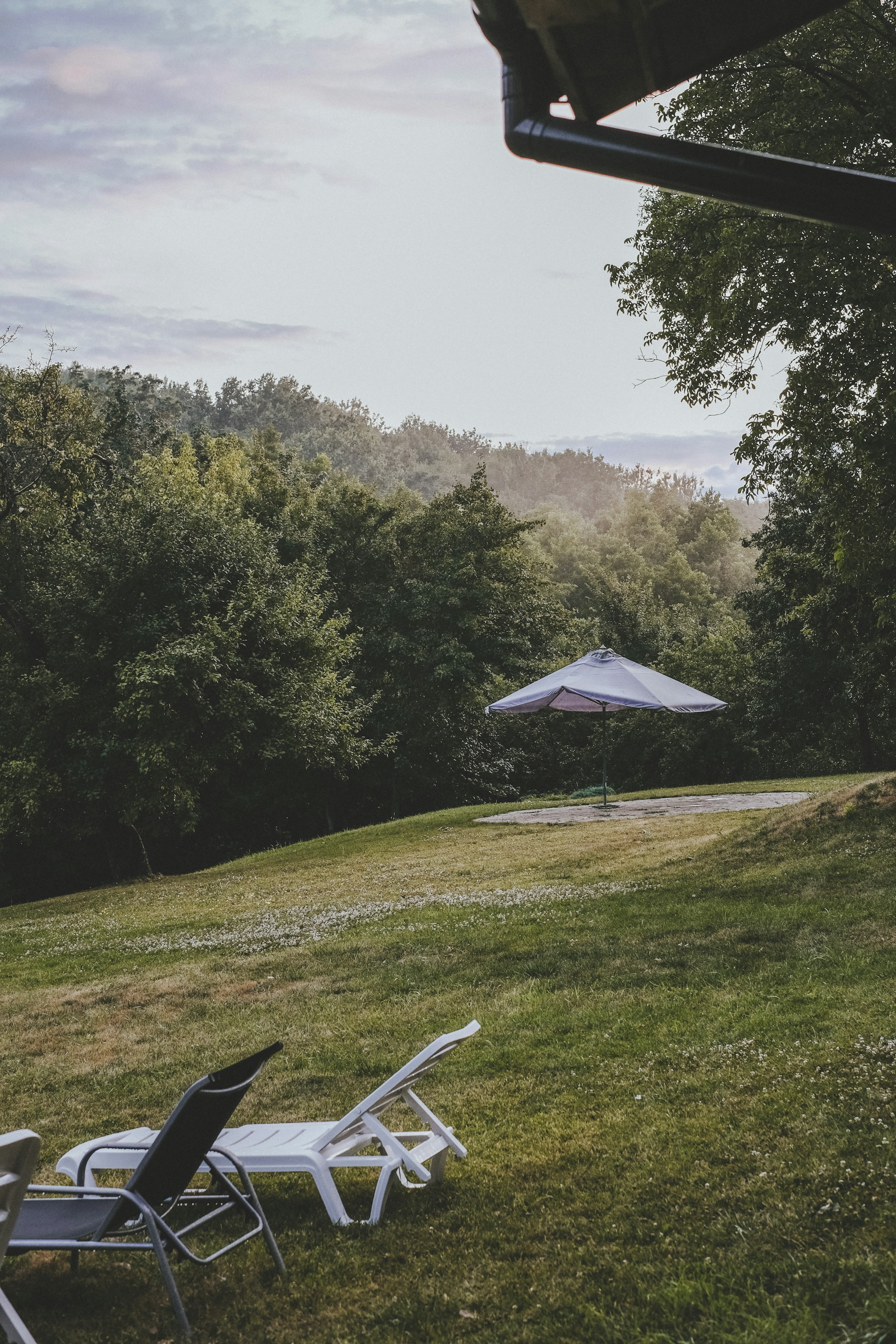 A serene outdoor lounge area at ruhespace.com with cozy seating surrounded by lush greenery under soft, warm lighting.