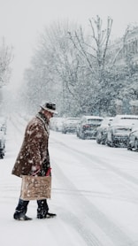 person in brown coat standing on snow covered ground during daytime