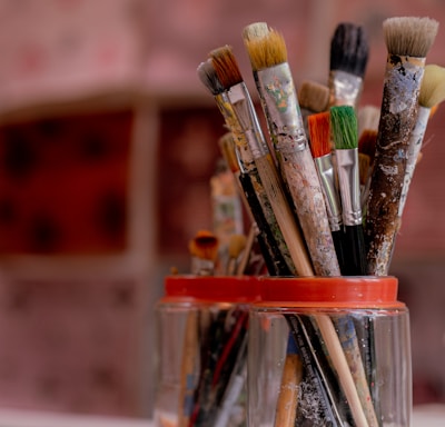 brown and red paint brush in clear glass container