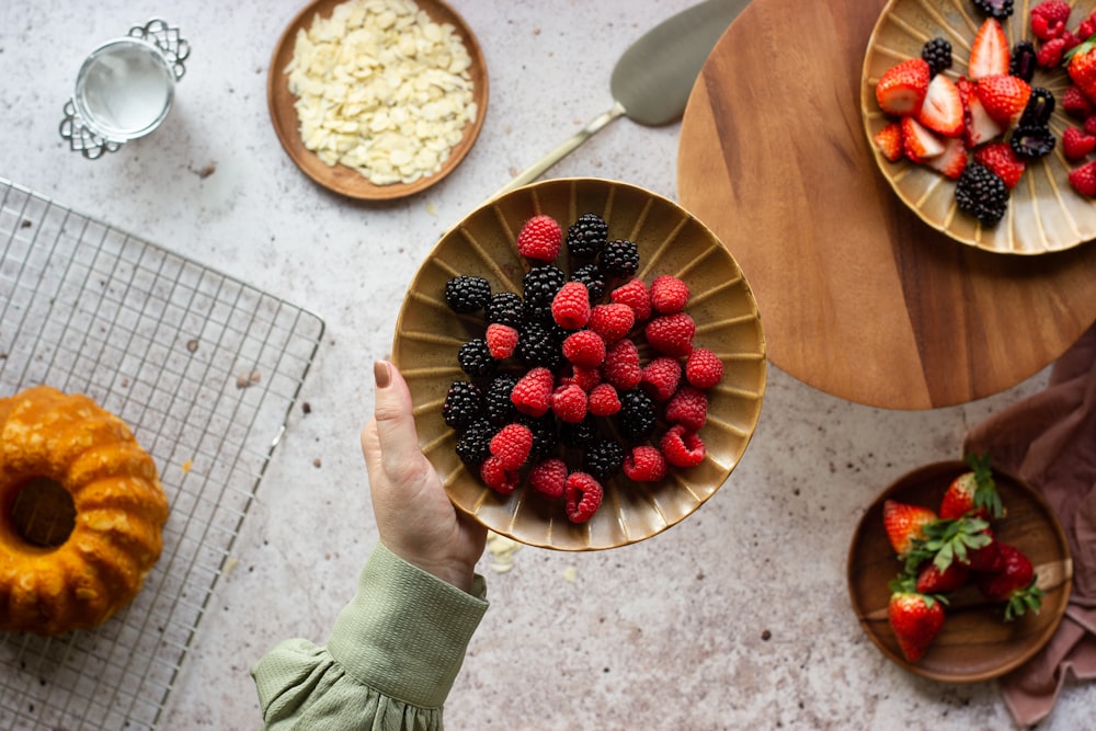 person holding bowl of strawberries