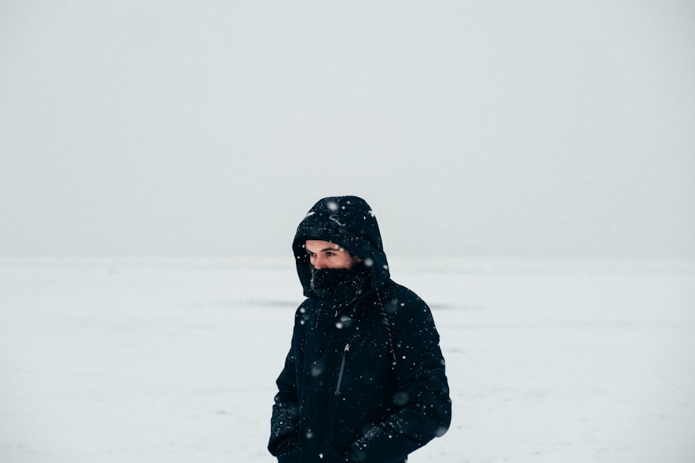 woman in black coat standing on snow covered ground