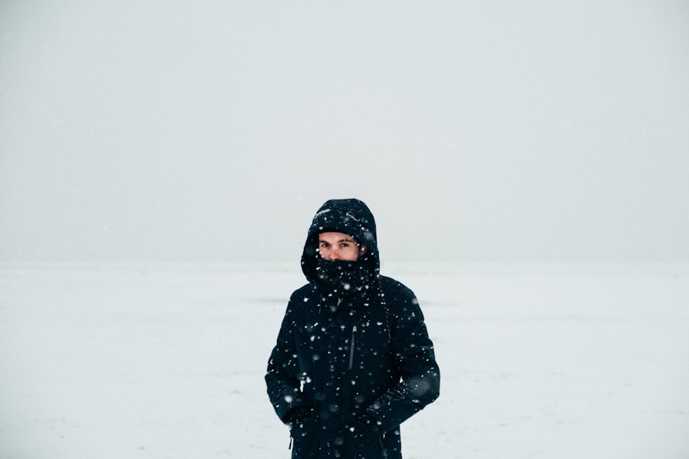 person in black hoodie standing on snow covered ground