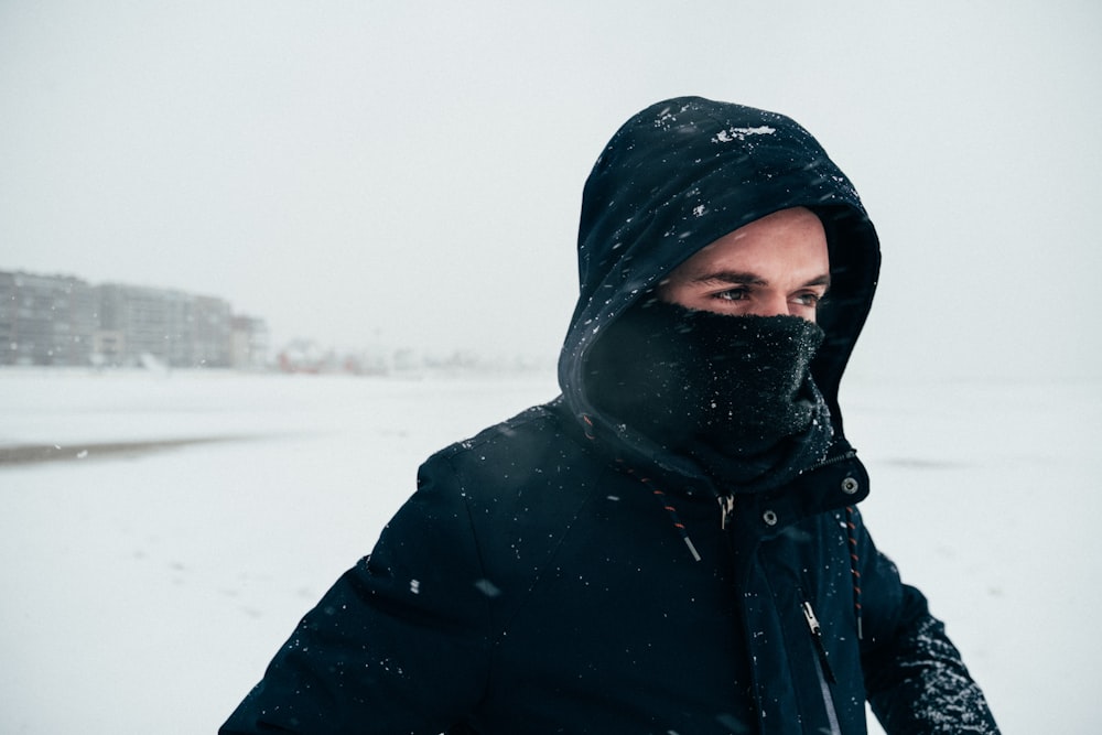 person in black hoodie standing on snow covered ground during daytime