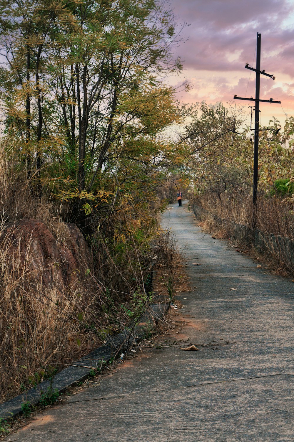 person in white shirt walking on gray asphalt road during daytime