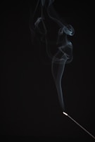 Soft shadows cast by a minimalist incense burner releasing wisps of fragrant smoke.