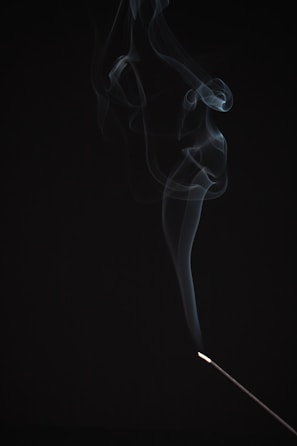 Soft smoke gently rising from an elegant incense burner against a deep green background.