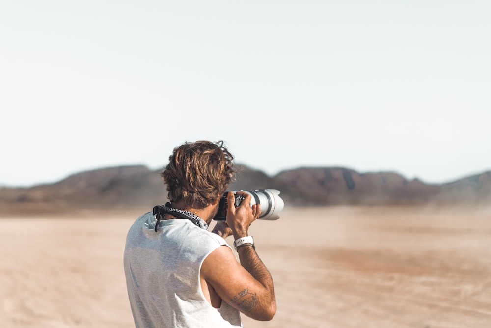 man in white t-shirt holding camera