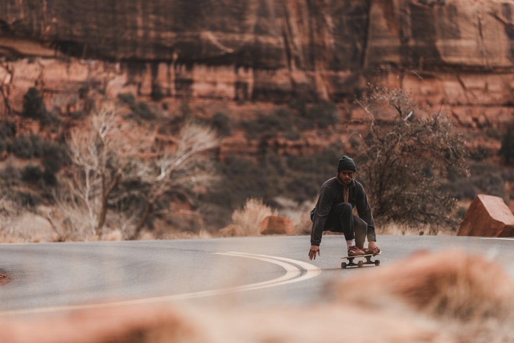 Mann in schwarzer Jacke fährt tagsüber Skateboard