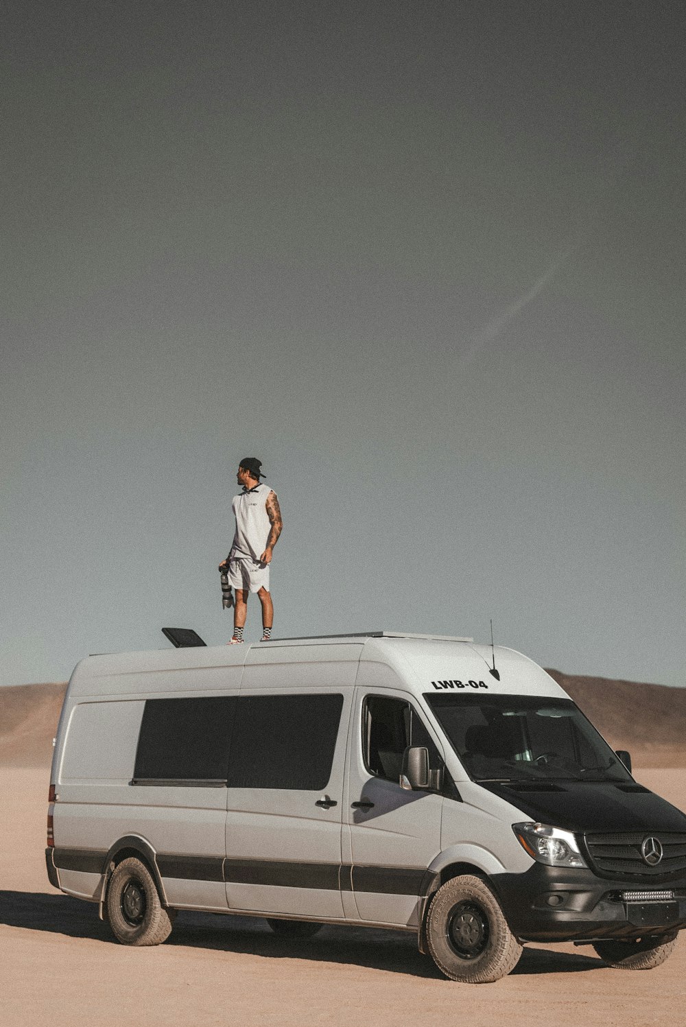 man in white t-shirt standing beside white van during daytime