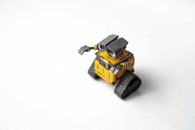 A bright yellow robot sticker with a friendly smile and geometric shapes.