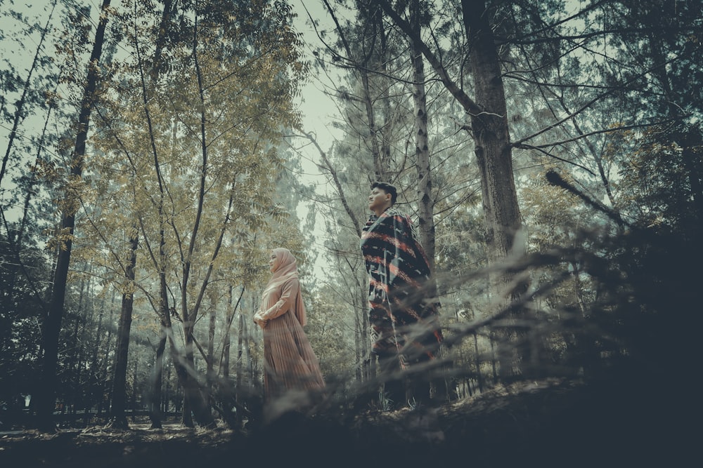 man and woman standing on forest during daytime