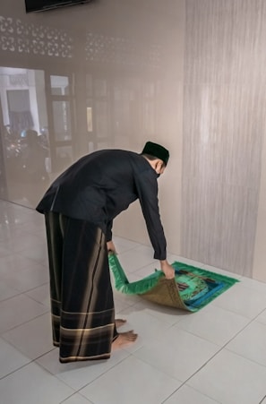 Black prayer rug rolled partially open beside a small indoor plant.