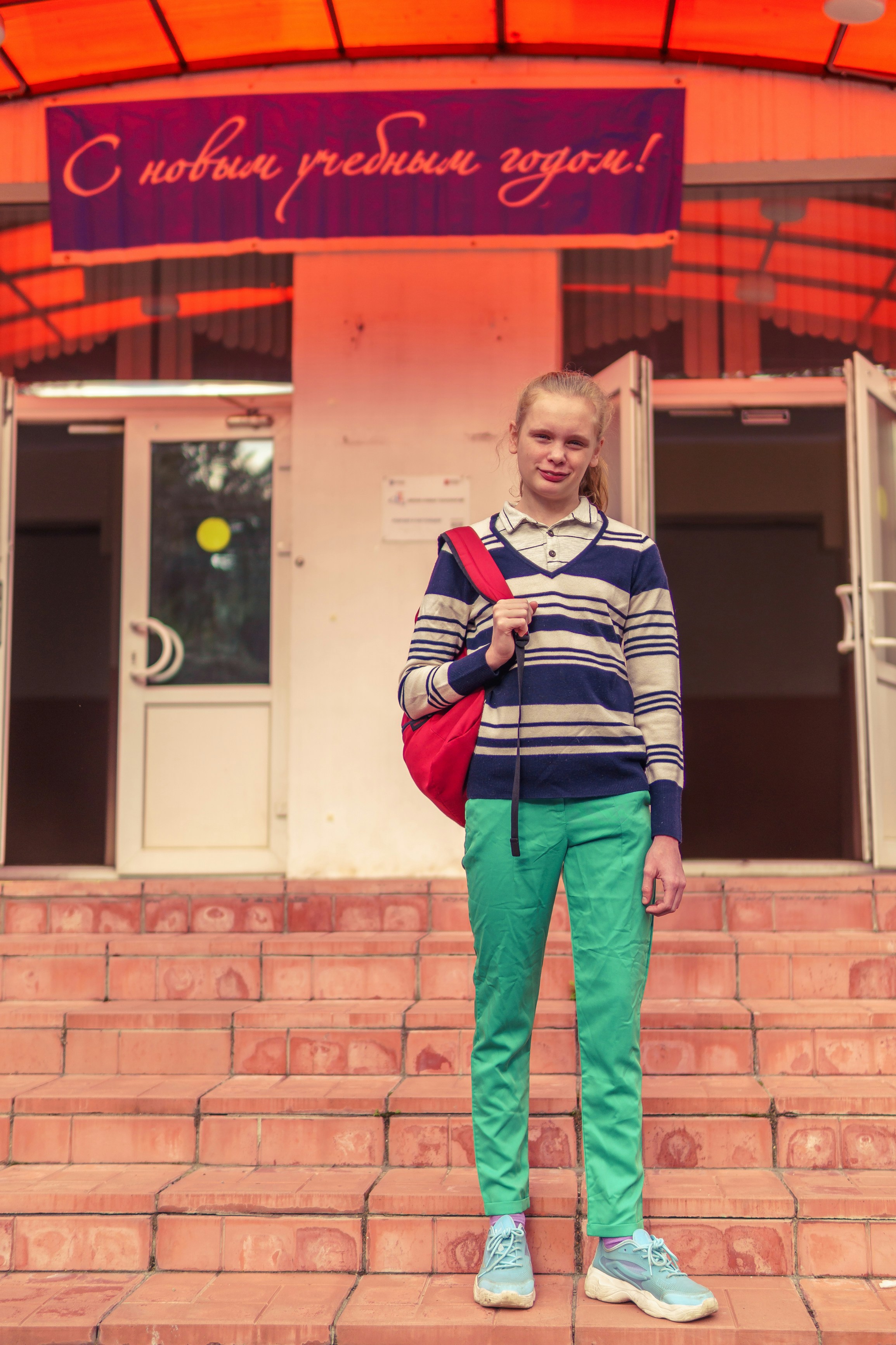 a girl stands in front of the school entrance