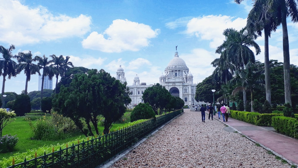 people walking on pathway near trees and building during daytime