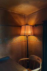 A cozy corner with a glowing, warmly lit lamp casting soft shadows on a bright, patterned rug.