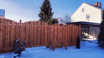 brown wooden fence near green tree under blue sky during daytime
