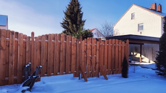 brown wooden fence near green tree under blue sky during daytime