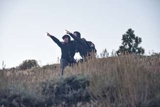 man in black jacket and black pants standing on brown grass field during daytime
