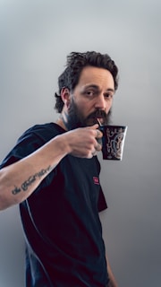 man in red and black crew neck t-shirt holding black and white ceramic mug