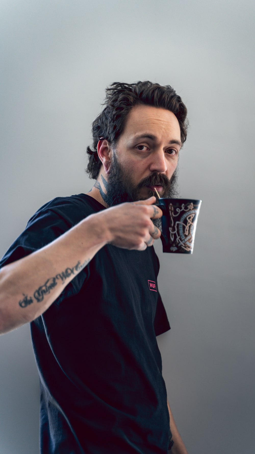 man in red and black crew neck t-shirt holding black and white ceramic mug