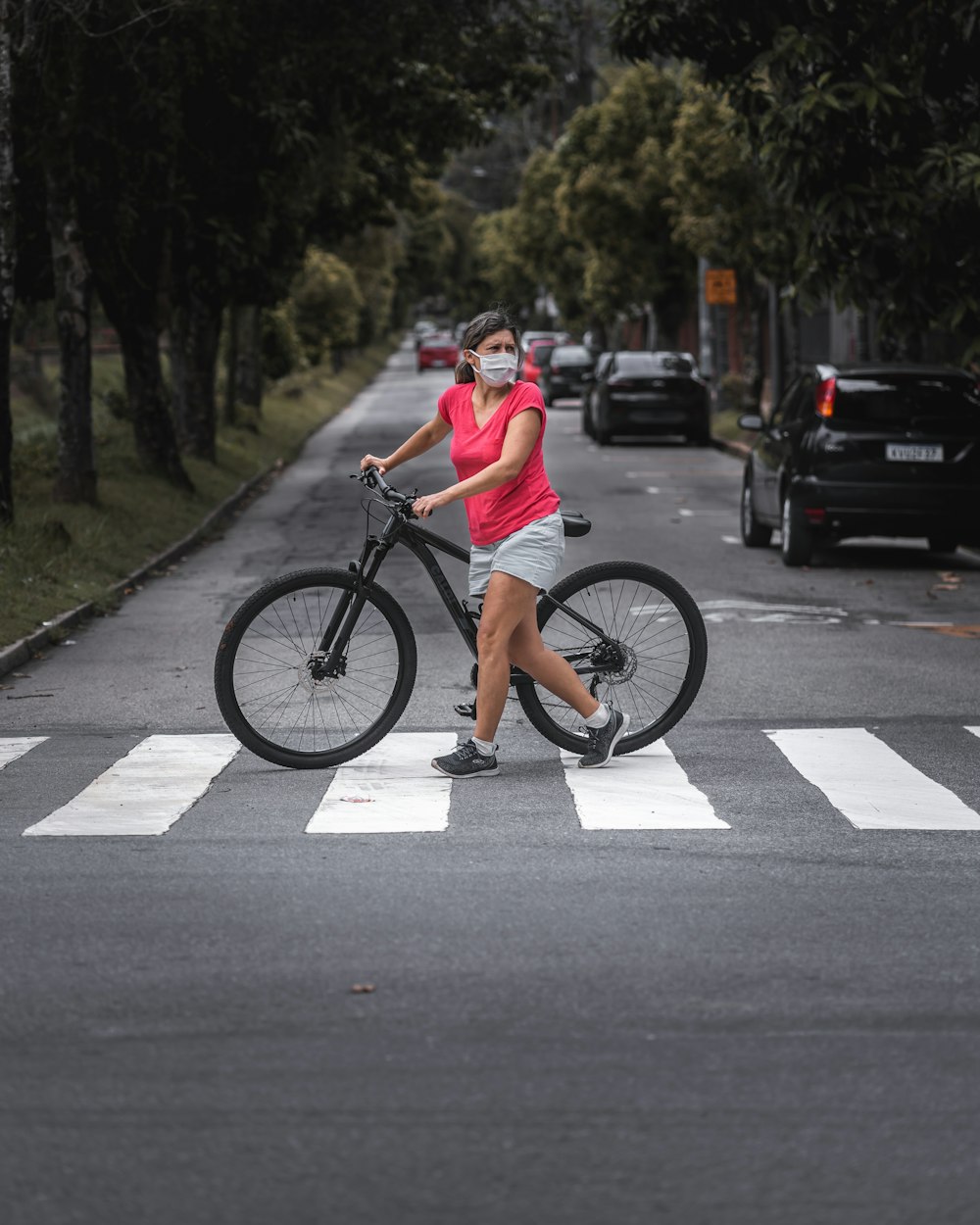 woman in gray tank top riding on black bicycle on road during daytime