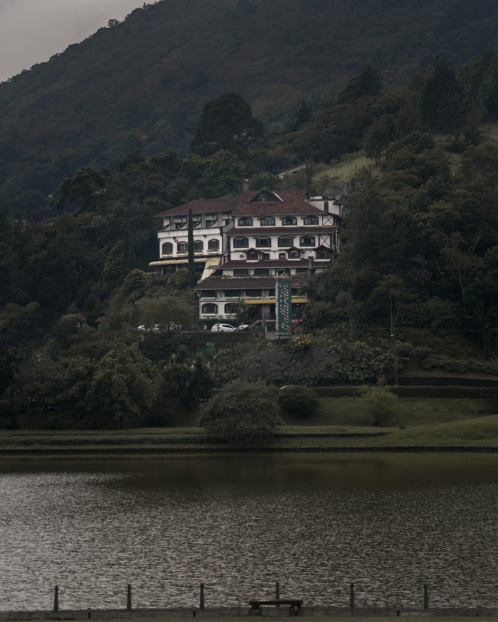 white and brown concrete building near green trees and lake during daytime