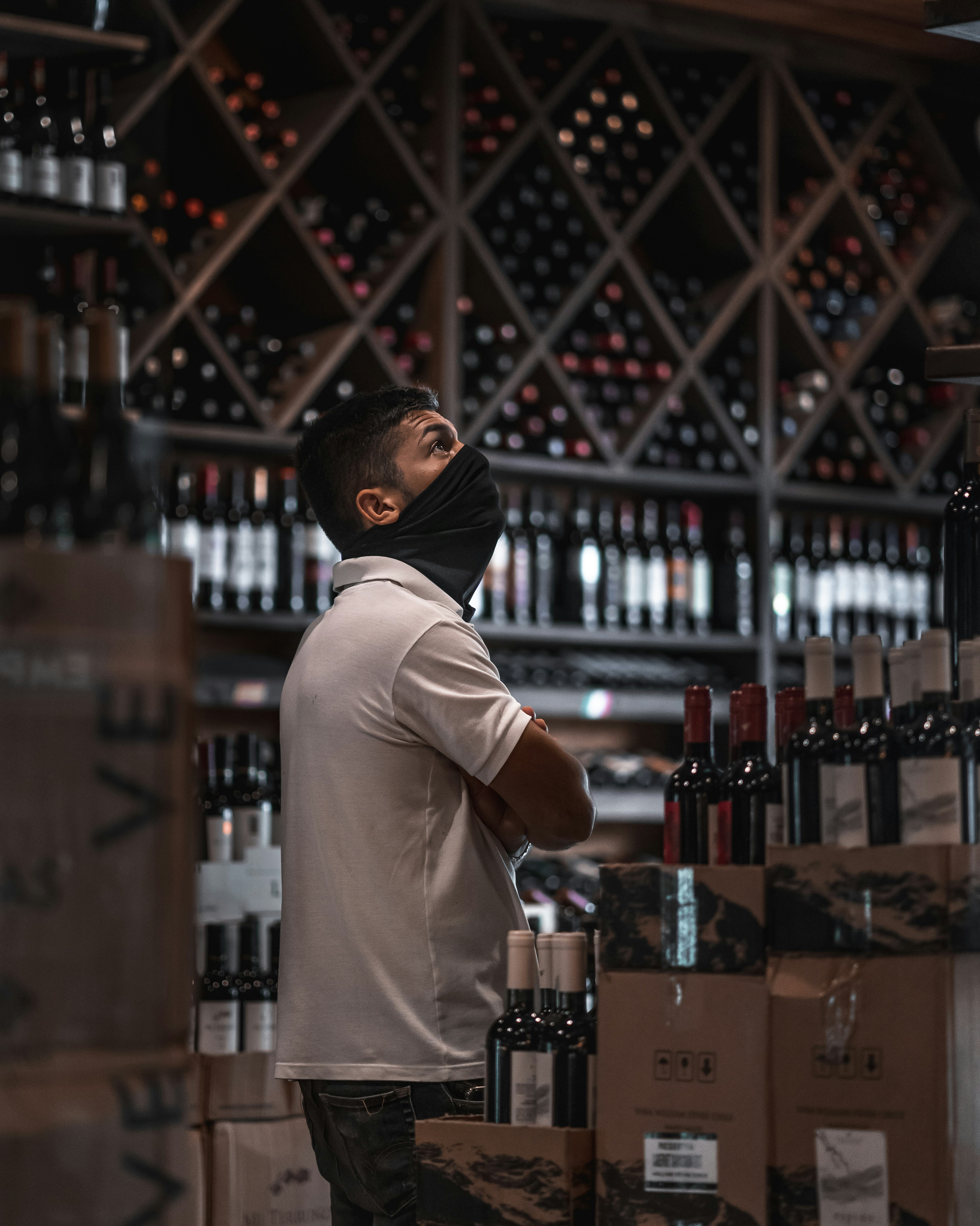 man in white t-shirt standing in front of brown wooden shelf