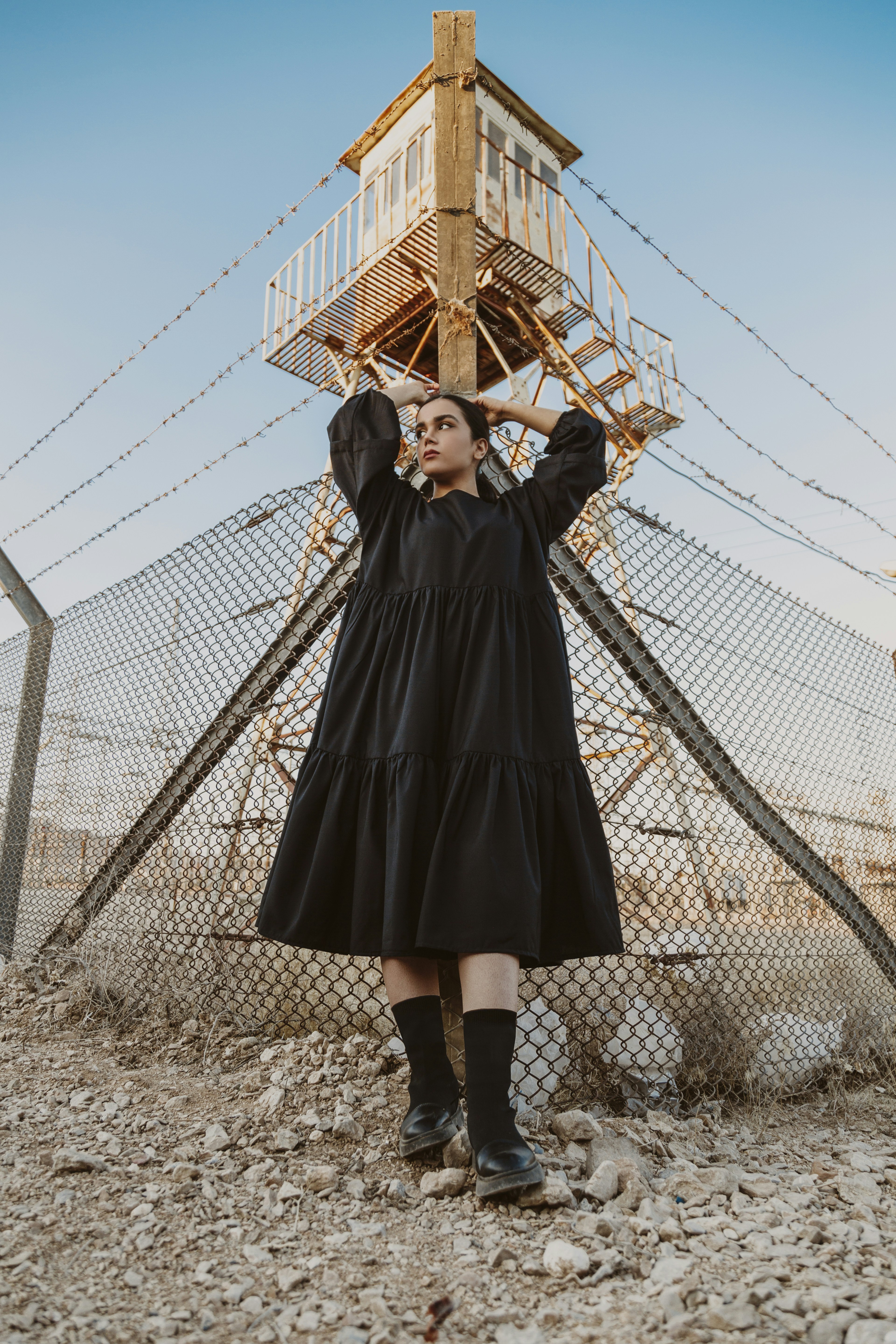 woman in black coat standing near gray metal fence during daytime