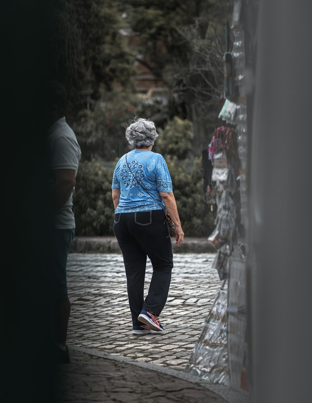 man in blue denim jacket and black pants walking on sidewalk during daytime