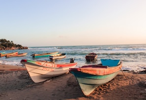 A panoramic view of a serene beach with fishermen preparing their boats early morning