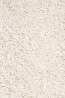 A close-up of a bowl filled with uncooked rice grains.