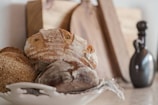 Hands gently placing a handcrafted bread centerpiece on a table with a rustic, textured backdrop.