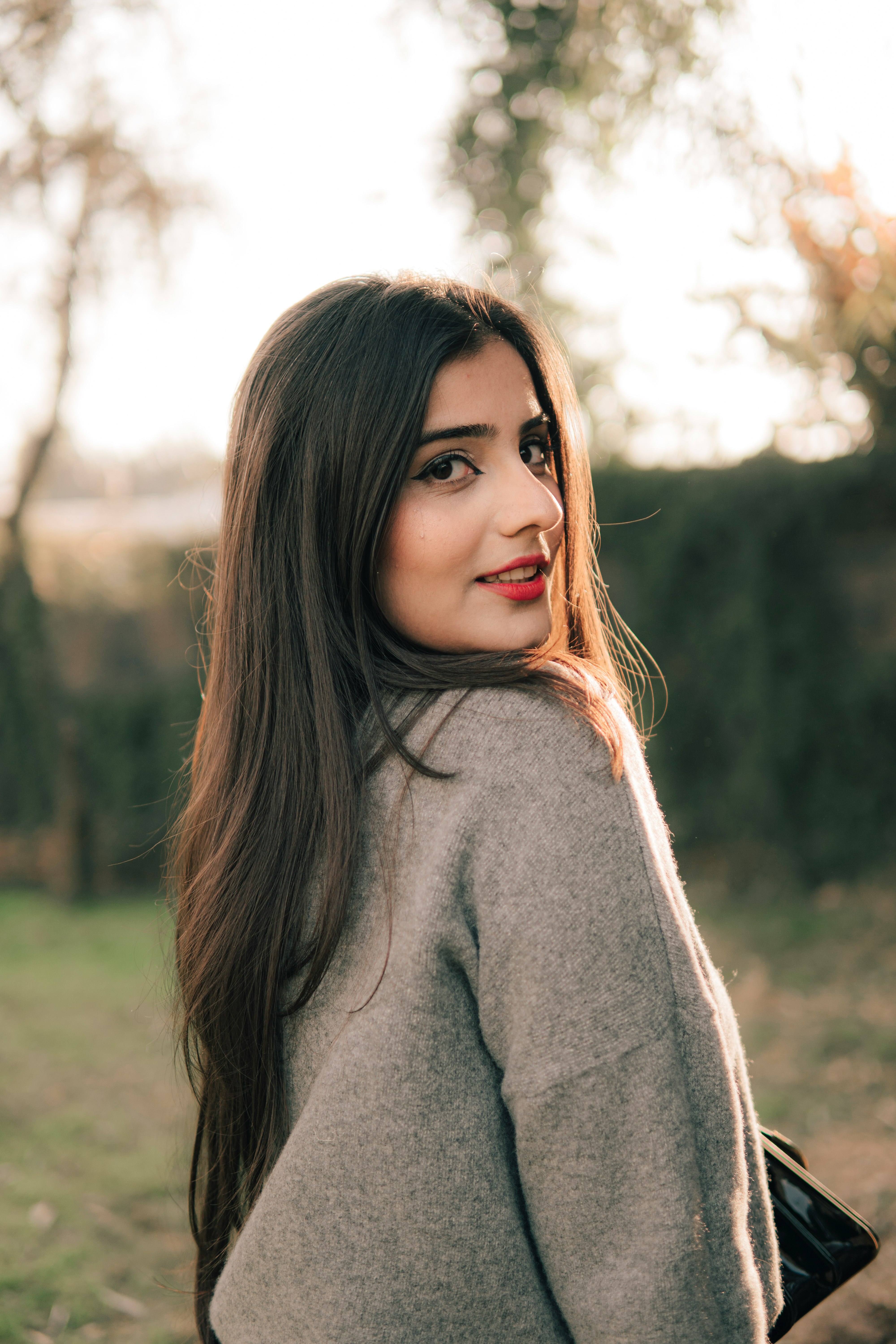 woman in gray turtleneck sweater standing on green grass field during daytime