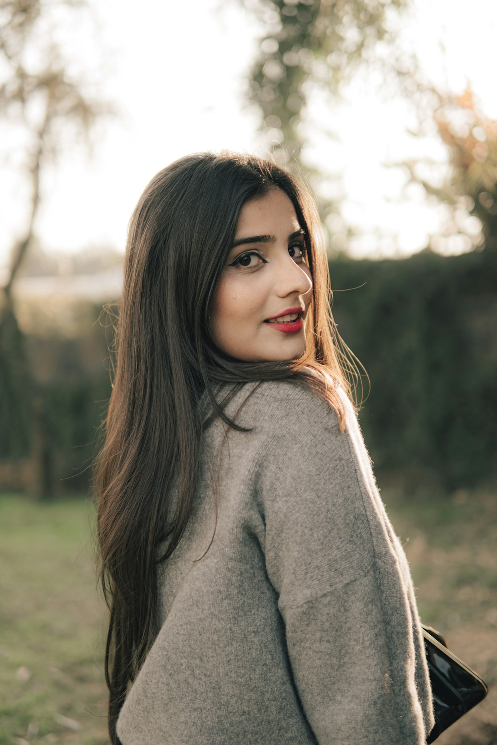 woman in gray turtleneck sweater standing on green grass field during daytime