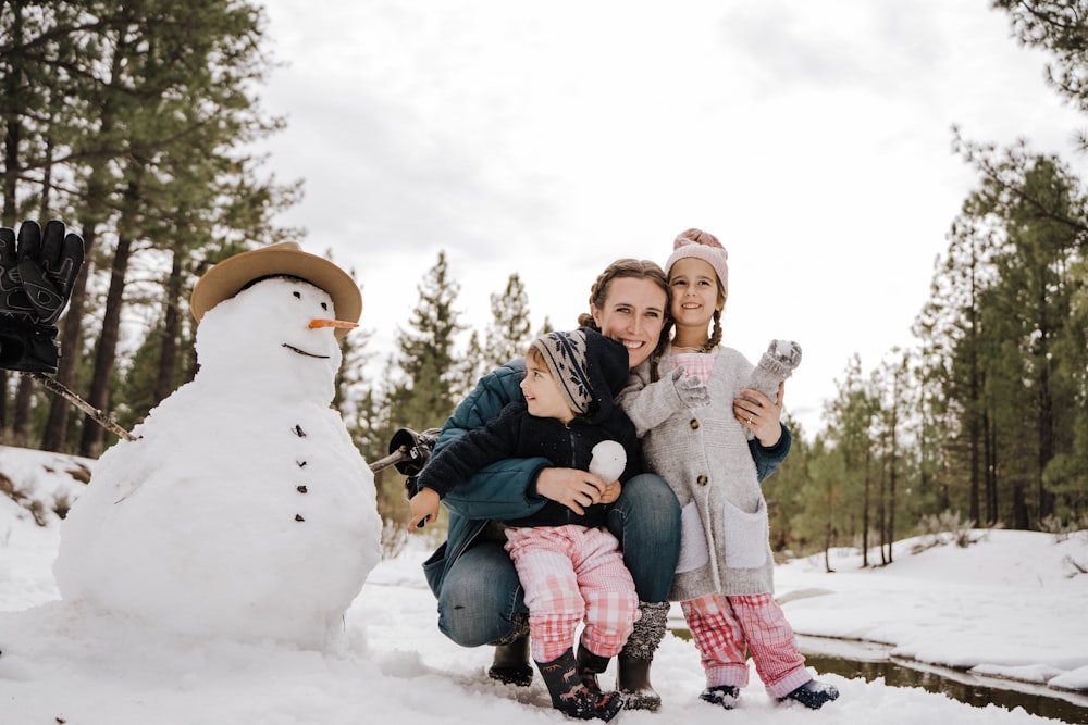 2 Mädchen sitzen auf weißem Schneemann