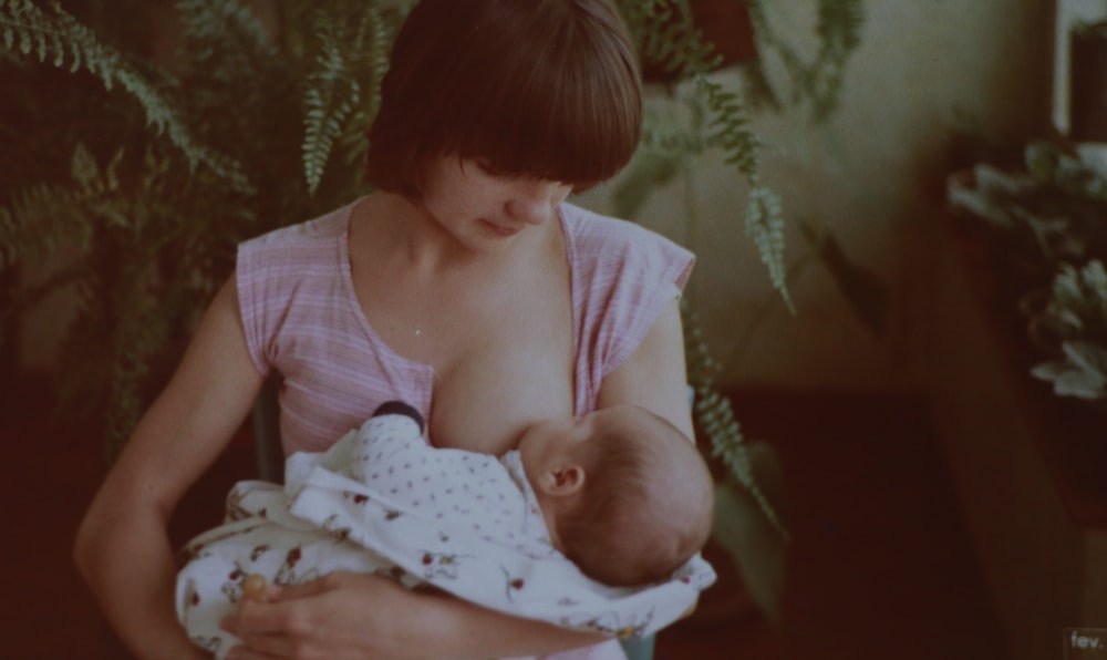 woman in pink tank top carrying baby