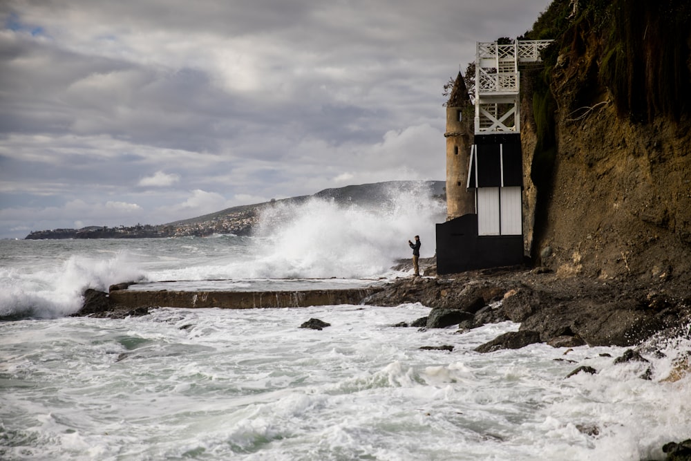 white concrete building near sea waves under white clouds during daytime